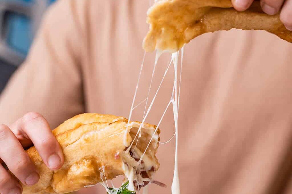 Four hands sharing a golden, crispy Neapolitan pizza fritta at Pizza Fritta 180 restaurant in Australia