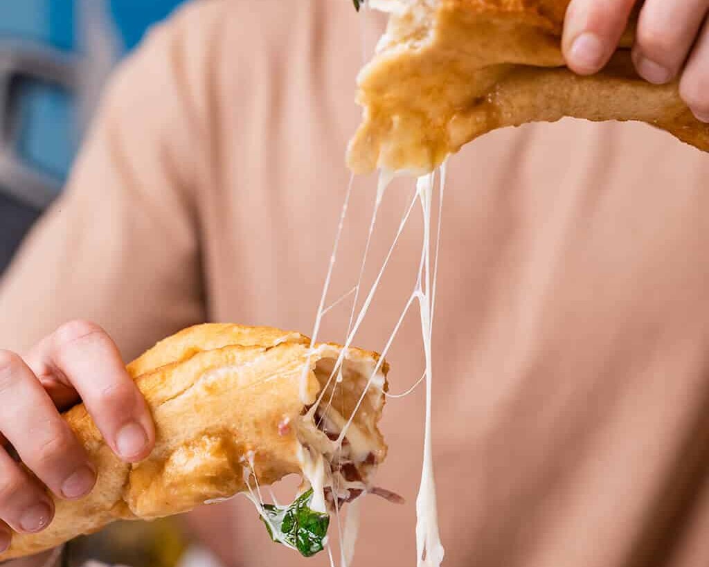 Four hands sharing a golden, crispy Neapolitan pizza fritta at Pizza Fritta 180 restaurant in Australia