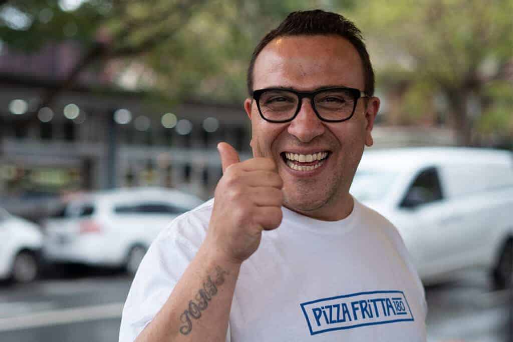Luigi Esposito, owner of Pizza Fritta 180, smiling and giving a thumbs up outside the restaurant