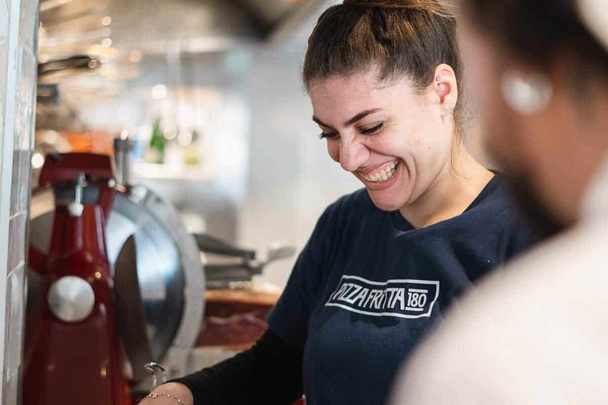Smiling female chef preparing food in kitchen at Pizza Fritta 180 restaurant